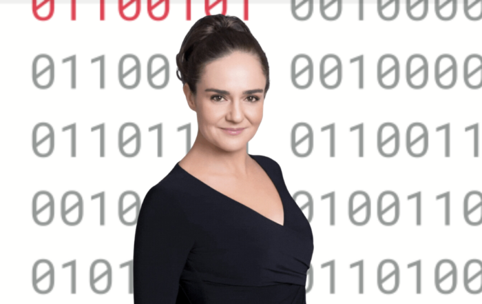 Anna Covert standing in front of a digital binary code background.